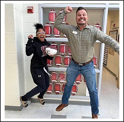 Both the insurance agent and the high school athlete are jumping in the air showing great team spirit after she receives the award.